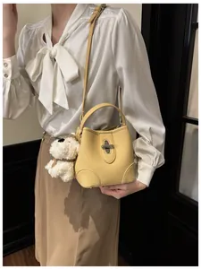 Detail view of yellow litchi pattern leather bucket bag with silver twist lock and charm