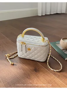 Detail of white quilted crossbody box bag with gold floral clasp and chain strap