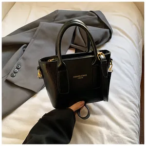 Detailansicht der schwarzen matten Ledertasche mit goldener Hardware und Logo-Druck