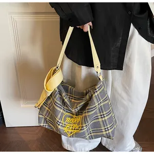 Detail of yellow heart embroidery on plaid tote bag with bow-tied leather strap