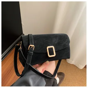 Detail of elegant black matte crossbody bag featuring a golden square metal buckle
