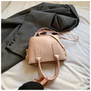 Nahaufnahme der rosa Kunstlederhandtasche mit Griffen und verstellbarem Riemen auf Stoff