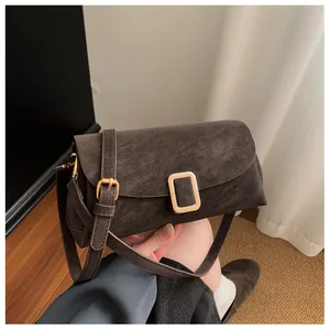 Detailed shot of dark coffee suede crossbody bag featuring gold buckle and leather strap