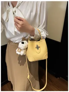 Detail of yellow bucket bag with lychee texture leather and plush puppy charm