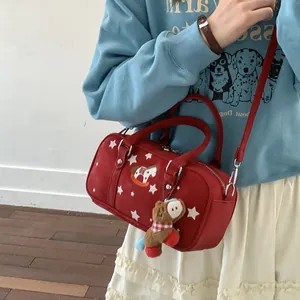 Red Boston handbag with star print and bear charm worn as a crossbody bag