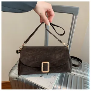 Close-up of dark brown suede shoulder bag featuring a sleek golden rectangular buckle