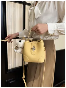 Detail of yellow bucket bag with lychee texture, silver twist lock and puppy pendant