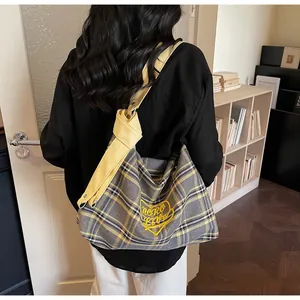 Detail of checkered tote bag with yellow shoulder strap and heart embroidery design