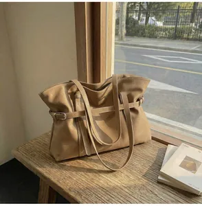 Detail der khakifarbenen Ledershopper mit Schnallenriemen auf einer rustikalen Holzbank