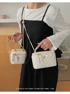 Detail of white quilted crossbody bag and mini handbag with gold floral accents