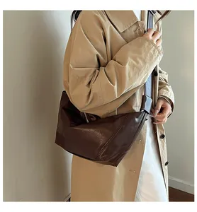 Detail of dark brown leather crescent bag with unique knotted wide shoulder strap design