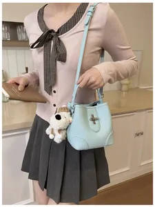 Detail of light blue bucket bag with pebble texture and cute puppy plush pendant