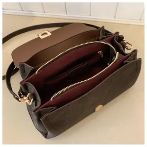 Detailed view of the brown suede crossbody bag with gold hardware and inner compartments