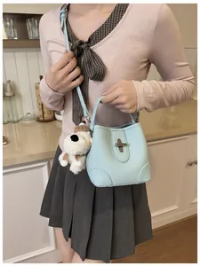 Detail of light blue bucket bag with leather texture and cute plush puppy charm
