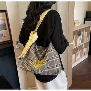Close-up of yellow plaid tote bag with heart embroidery and knotted shoulder strap detail