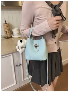 Light blue lychee pattern bucket bag featuring a gold metal lock and plush puppy charm