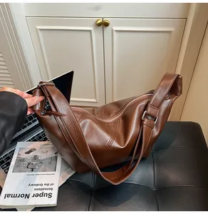 Close-up of brown vintage crossbody bag with wide strap and silver metal buckle