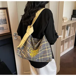 Detail of grey plaid tote bag with yellow heart embroidery and knotted leather strap