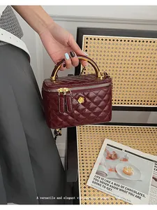 Detailed close-up of wine red quilted vanity case bag with gold camellia clasp decoration