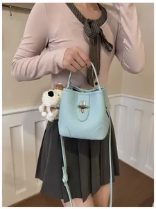 Detail of light blue bucket bag with pebble leather and cute dog charm pendant