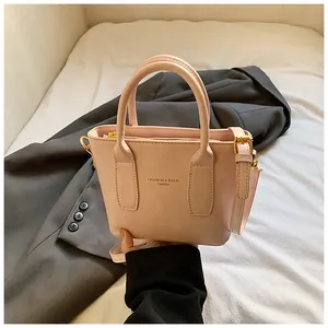 Detailaufnahme der nuderosafarbenen Lederhandtasche mit Goldbeschlägen und Logo-Prägung
