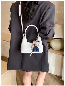 Glossy white minimalist handbag with adjustable shoulder strap and blue denim bear charm