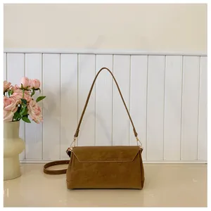 Front view of a vintage brown suede crossbody bag with gold hardware and slim strap