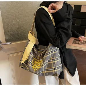 Detail of yellow checkered tote bag with heart embroidery on a black outfit