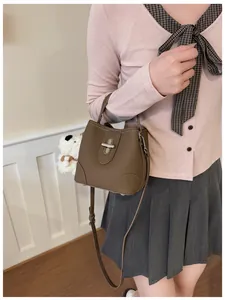 Close-up of brown bucket bag with silver twist lock and cute white plush dog charm