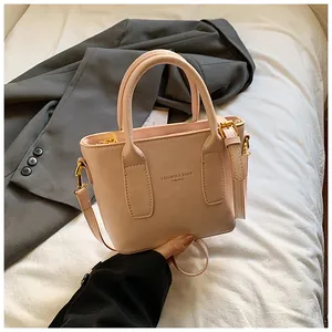 Detail der hellrosa Handtasche aus Kunstleder mit Riemen und goldener Markenschrift