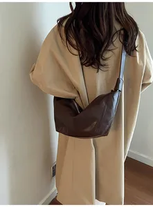 Detail of dark brown pleated dumpling bag showing synthetic leather texture and half-moon shape