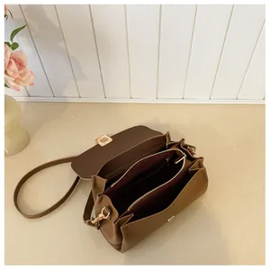 Interior detail of tan square bag showing dual compartments and burgundy lining