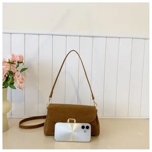 Brown suede shoulder bag detail with gold metal buckle and phone size comparison