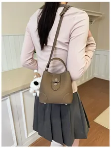 Rear view of a leather bucket bag in dark khaki with a cute plush dog pendant