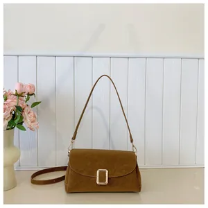 Macro shot of minimalist brown suede crossbody bag featuring elegant gold rectangular clasp