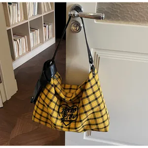 Detail view of large checkered tote bag with heart embroidery hanging on a door handle