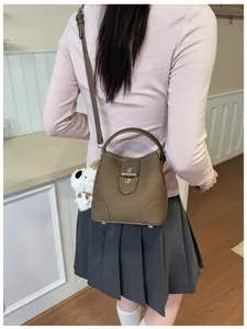 Detail of a brown leather bucket bag with silver twist lock and plush puppy charm