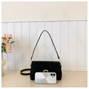 Detail view of black suede shoulder bag size compared with a silver smartphone