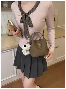Detail of dark brown bucket bag with lychee texture leather and a cute dog plush charm