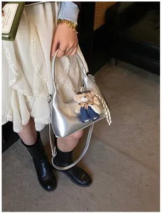 Detail of silver metallic handbag with a cute plush bear charm on white lace dress