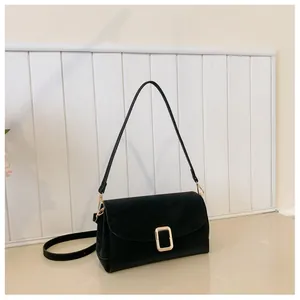 Detail of minimalist black square bag with matte texture and golden rectangular metal clasp