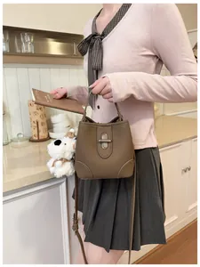 Detail of brown litchi pattern leather bucket bag with silver lock and plush puppy charm