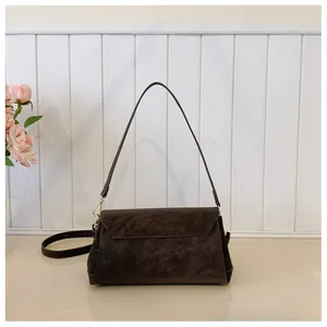 Detail of dark brown matte suede shoulder bag with golden buckle and interchangeable strap