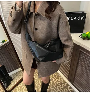 Model wearing a black wrinkled leather dumpling bag with retro texture and strap