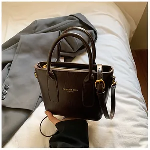 Detailansicht einer dunkelbraunen Vintage-Eimertasche mit Goldbeschlägen auf grauem Sakko