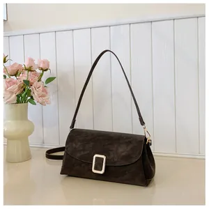 Close-up of dark coffee suede shoulder bag with elegant gold buckle on wooden background