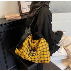 Detail of yellow plaid canvas tote bag with black leather strap and artistic embroidery