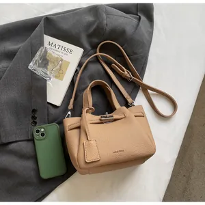 Détail d'un sac seau en cuir beige grainé avec fermoir rotatif et bandoulière réglable