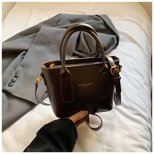 Detail einer dunkelbraunen Ledertasche mit goldenen Beschlägen und Logoprägung