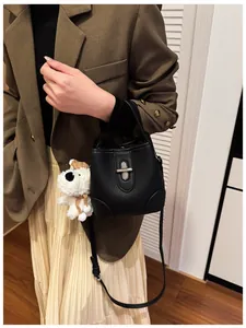 Detail of black leather bucket bag with silver clasp and cute white dog plush pendant
